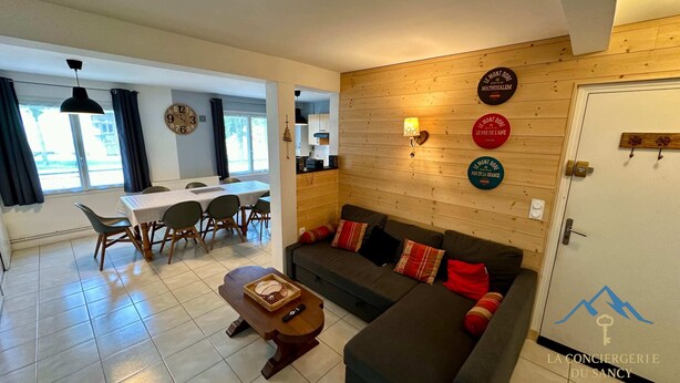 Una sala de estar moderna con un sofá, una mesa de comedor con sillas y una pared de madera decorada con platos.
