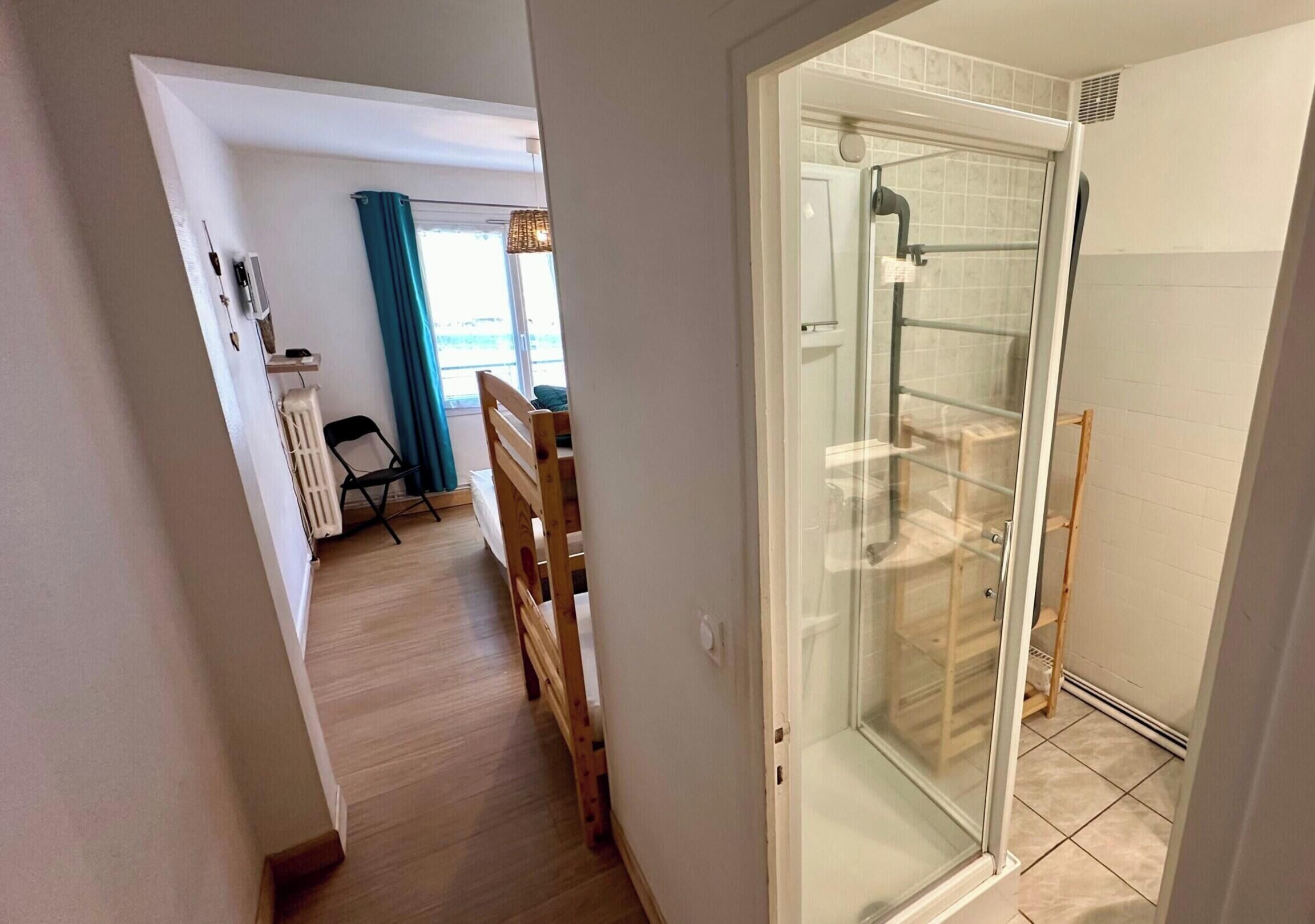 A narrow hallway leading to a glass-enclosed shower area with a tiled floor.