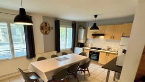 Cocina compacta con una mesa de comedor, sillas, un reloj y vistas al exterior.