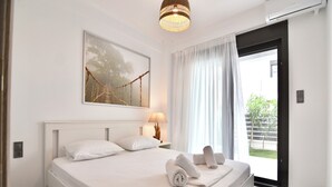 A hotel room with a bed, a painting, a lamp, and a view of the outdoors. - Renata Apartment in Nikiti (Sithonia)