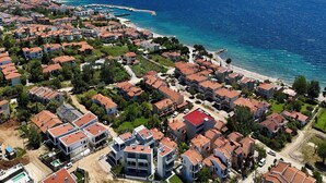 An aerial view of a coastal residential area with houses, a beach, and a marina. - Renata Apartment in Nikiti (Sithonia)