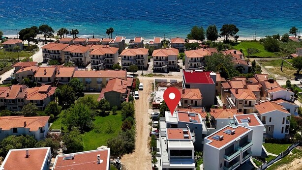 A coastal residential area with terraced houses, a clear view of the sea, and a marked location pin. - Renata Apartment in Nikiti (Sithonia)