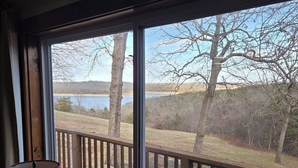 A room with a large window overlooking a deck and a lake. - Norfork Lakeview Oasis House #12 at Teal Point Resort (Mountain Home)