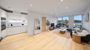 A modern apartment with a kitchen, living area, and large windows offering a view. - Comfy 2 BR+ Free Parking Gym, Game Rooms, & Cinema (London)