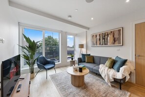 Una sala de estar moderna con sofá, mesa de centro y un ventanal grande.