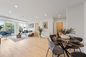 Un salon moderne comprenant un coin repas, de grandes fenêtres et une vue sur l’extérieur.