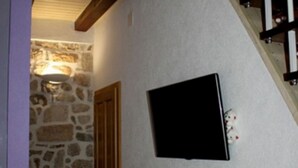 A room with a stone wall, a wooden door, and a black framed object on the wall.
