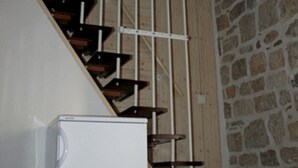 A staircase with wooden steps and metal railings, leading to a stone wall.