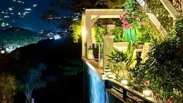 Ein Gebäude bei Nacht mit Balkon, Weg und Garten.
