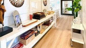 Ein modernes Interieur mit Holzboden, weißen Wänden und einem langen, weißen Regal mit Büchern und Dekoration.