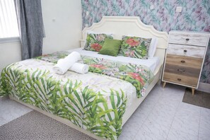 Een bed met bloemenbedekte lakens, een nachtkastje en een nachtkastje met lades.