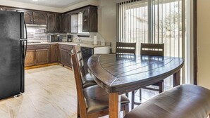 A kitchen with dark wooden cabinets, a black refrigerator, and a dining area with a round table and chairs. - 8 Mi to Bricktown Fun: Quiet Family Retreat (Oklahoma City)