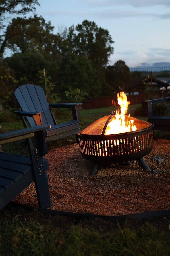 A fire pit with flames, surrounded by outdoor seating.