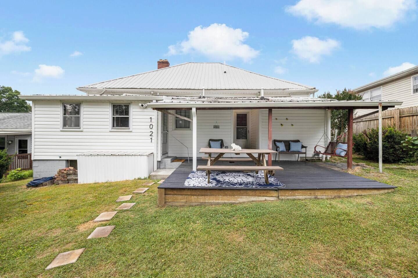 A two-story house with a covered patio area featuring a picnic table and outdoor seating.