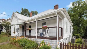 Une maison blanche d’un seul étage, dotée d’un porche, portant le numéro 102, avec des fondations en pierre et une clôture en bois.
