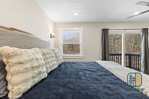 Ein Schlafzimmer mit einem großen Bett, einem Fenster und einem Balkon mit Vorhängen.