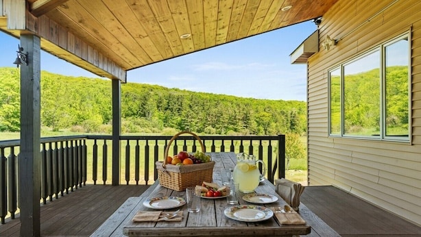 Eine Holzterrasse mit Esstisch, umgeben von einer Geländer, mit Blick auf eine üppige, grüne Landschaft.