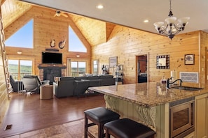 A spacious living area with a fireplace, a large TV, and a kitchen with granite countertops.