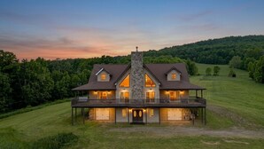 Ein großes, zweistöckiges Haus mit einem Steinsschornstein, zahlreichen Fenstern und einer Veranda.