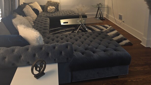 Een moderne woonkamer met een hoekbank, een witte salontafel en een wandgemonteerde flatscreen-tv.