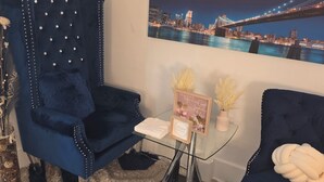 Een gezellige woonkamer met uitzicht op de stad, een blauwe fauteuil, een glazen salontafel en een decoratief vloerkleed.