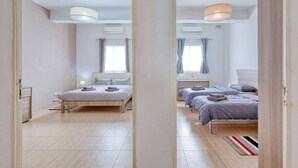 Makuuhuoneessa on kaksi sänkyä, puulattia ja ikkuna, jossa on verhot.