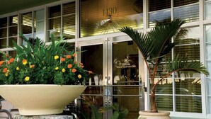 L’entrée d’un hôtel, agrémentée d’un grand bac à fleurs, d’un palmier et d’une enseigne indiquant « Hilton Grand Vacations Club ».