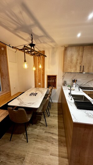 Une cuisine moderne dotée d’un plan de travail en marbre, de meubles en bois et d’un lustre original.