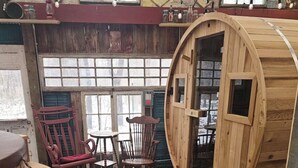 Een rustiek houten interieur met een groot, vatvormig raam, houten meubels en een geweven vloerkleed.