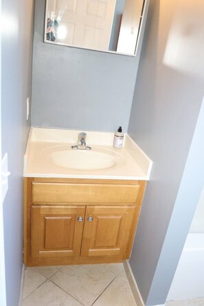 A bathroom with a white sink, wooden cabinets, and a mirror above the sink. - Modern 1BR/1BA Apartment - Self Check-In (Belleville)