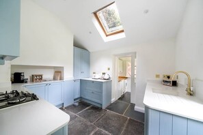 A compact kitchen with blue cabinets, a gas stove, and a skylight.