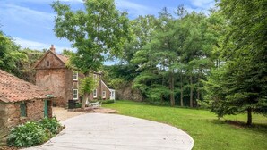 A stone house with a wooden deck and a grassy yard. - Idyllic Waterside Georgian Cottage (Halberton)