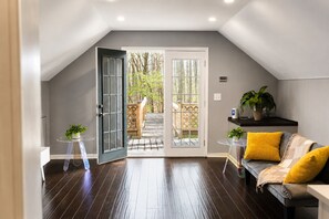 An interior with a wooden deck, a sofa with yellow cushions, and a small table with a plant.
