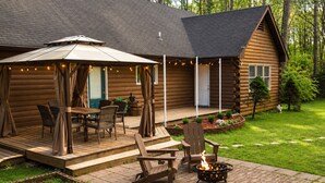 A log cabin with a patio, outdoor seating, and a fire pit.