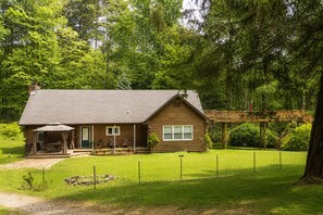 A log cabin with a porch, a covered patio, and a fenced yard.