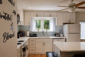 A kitchen with white cabinets, a window with curtains, a ceiling fan, and a refrigerator. - Fully Fenced Yard - Dog-Friendly Only - No Smoking- Sleeps 6 - Alpharetta (Alpharetta)