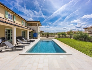A swimming pool area with lounge chairs and a building with a tiled roof. - Elegant Family Retreat With Pool in Istria (Zminj)