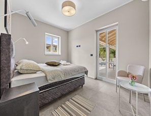 A modern bedroom with a bed, a desk, a chair, and a view of the outdoors. - Elegant Family Retreat With Pool in Istria (Zminj)