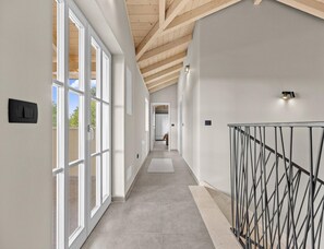 A modern hallway with a high ceiling, large windows, and a metal railing. - Elegant Family Retreat With Pool in Istria (Zminj)