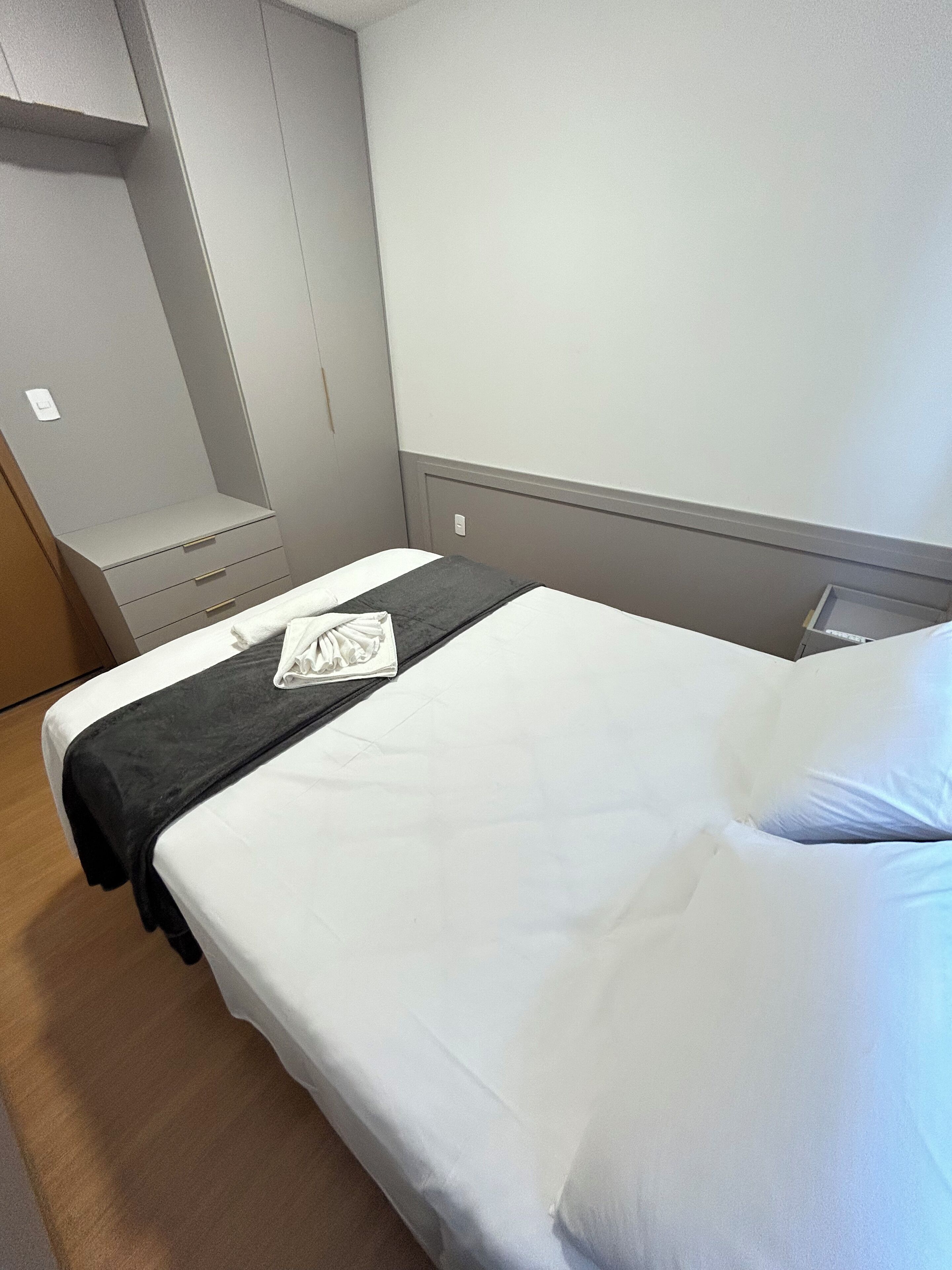 Una camera d'albergo con un letto, un comodino, un armadio e un interruttore a parete.