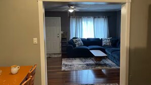 Ein Wohnzimmer mit einem dunkelblauen Sofa, einem Couchtisch und einem gemusterten Teppich.