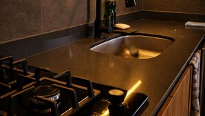 A modern kitchen with a gas stove, a black faucet, and a countertop. - Cabin with Jacuzzi in front of the Guatapé Lake. (Peñol)