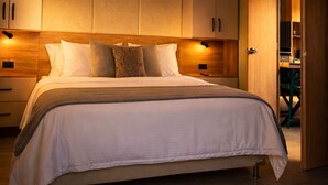A bedroom with a bed, wooden cabinets, and a door leading to another room. - Cabin with Jacuzzi in front of the Guatapé Lake. (Peñol)