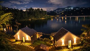 Two modern, lighted cabins by a lake at night with a mountain backdrop. - Cabin with Jacuzzi in front of the Guatapé Lake. (Peñol)