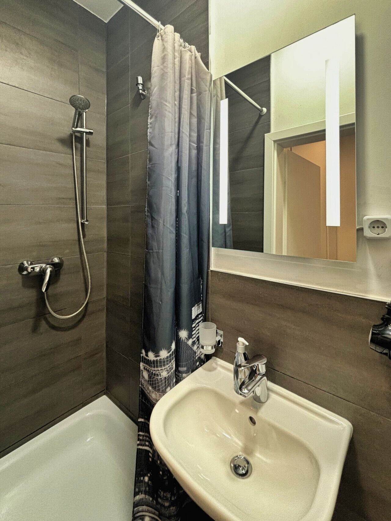 Ein Badezimmer mit Dusche, Waschbecken und Spiegel.