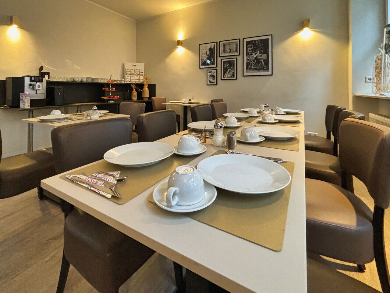 Comedor con mesas dispuestas para cuatro, con platos blancos, tazas y cubiertos.