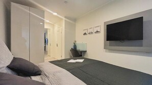 A bedroom with a bed, a wardrobe, a desk, and a TV.