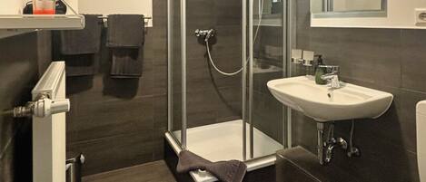 Une salle de bain moderne avec une douche à parois de verre, un lavabo blanc et des toilettes.