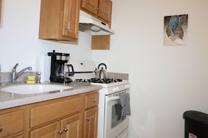 Una cocina con armarios de madera, una cafetera, un hervidor y una estufa.