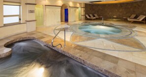 Ein Wellnessbereich mit Whirlpool, einer kleinen Wasserfall und Liegestühlen.